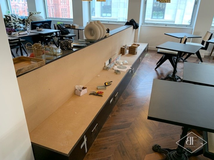 Long timber-topped storage counter with dark base units dividing a breakout seating area