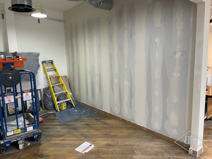 New partition wall with skim coat patches drying, access platform standing nearby