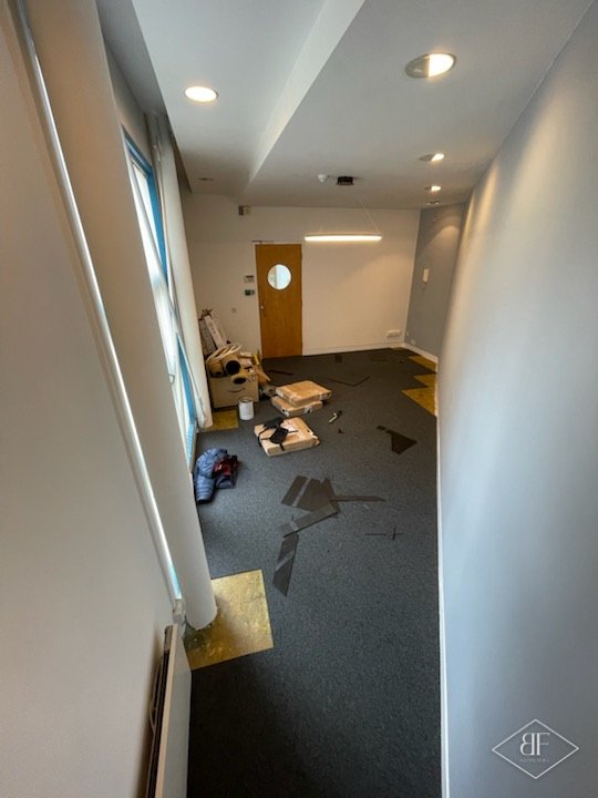 Narrow office corridor with new dark carpet tiles and freshly decorated walls