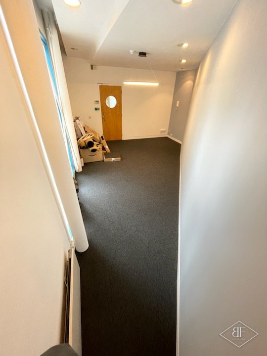 Finished corridor with dark carpet tiles and clean decorated walls