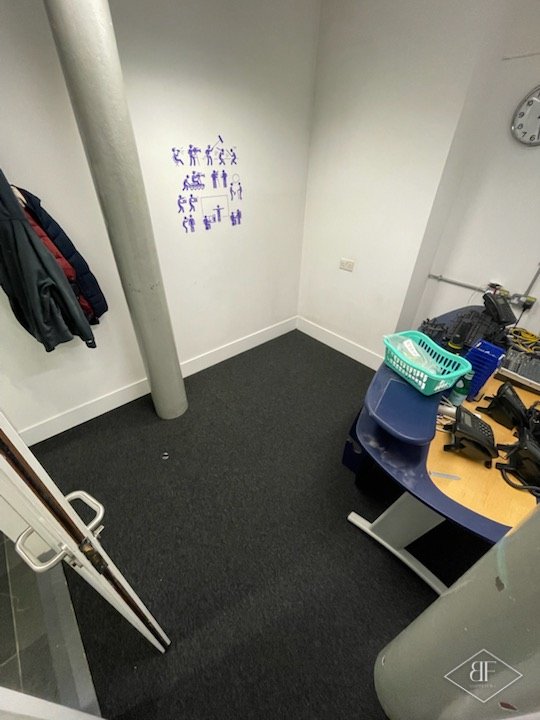 Compact office with white walls and new dark carpet tiles around a column