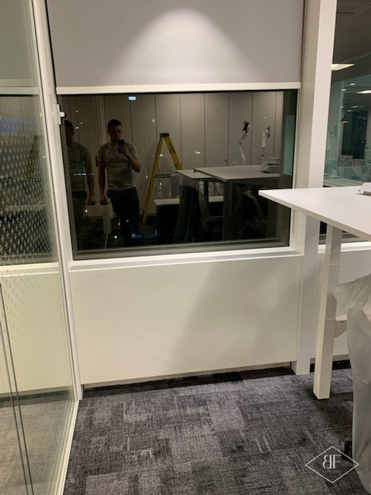Finished white panel beneath an office window beside a glazed partition