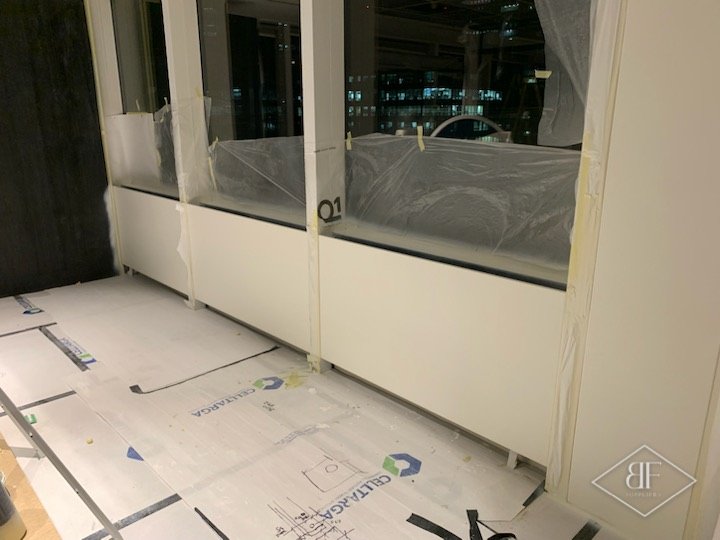 Taped and masked window frames above white panels with floor protection laid