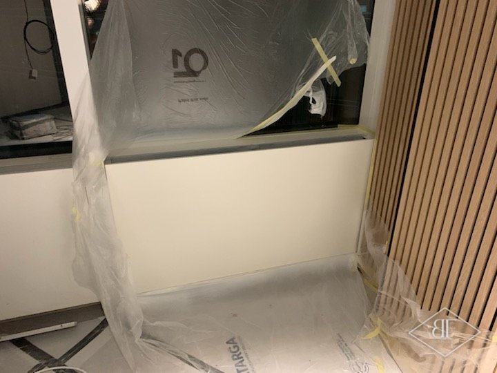 Freshly sprayed white perimeter panel below the window, with dust sheeting taped in place