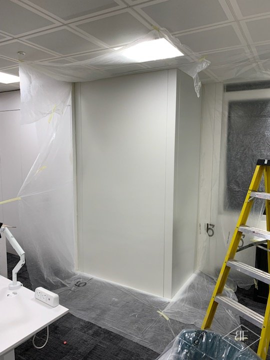 Office corner with newly sprayed white panelling, finished and ready for fit out