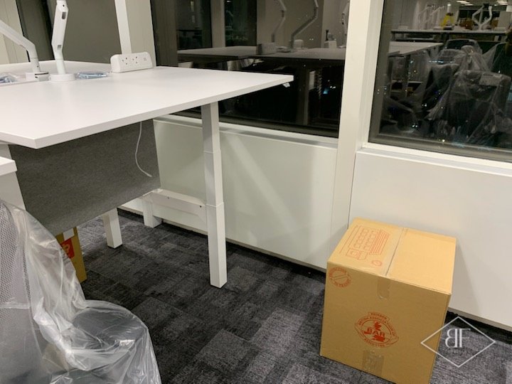 Sprayed white panels beneath a desk in a London office with new carpet tiles