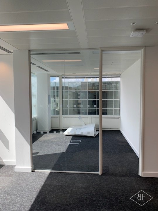 Glass-fronted meeting room with timber-trimmed partition and window behind, London office