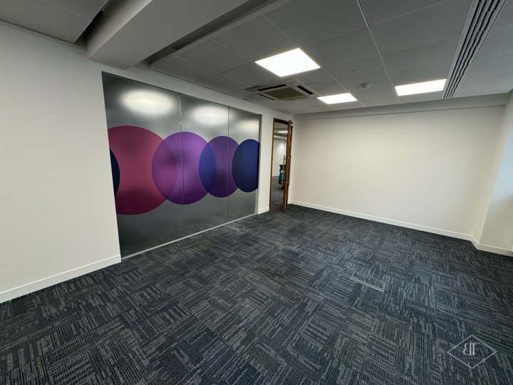 Large room with decorative circle graphic on glazed partition and new carpet tiles