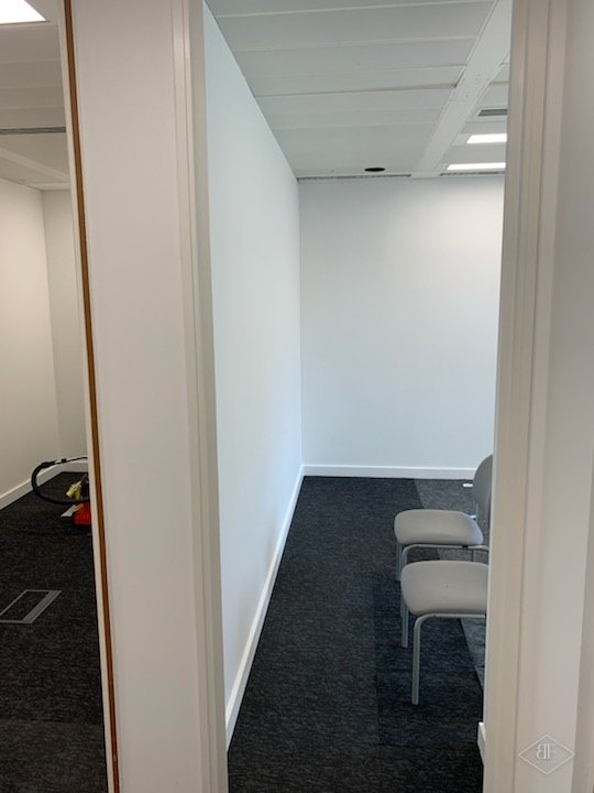 New plasterboard partition wall beside a timber-edged door opening and chairs