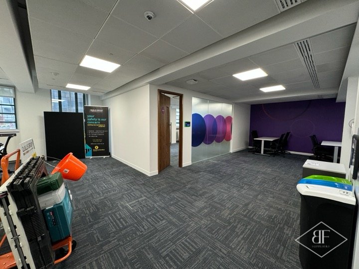 Office floor with finished partitions, purple feature wall and tools being packed away