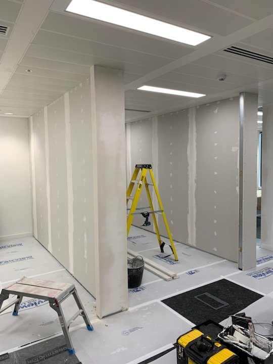 Plasterboard partition with joints being finished, stepladder and protected floor