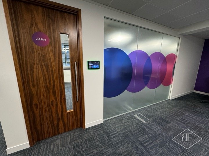 Close view of walnut door beside printed glazed partition with coloured circles