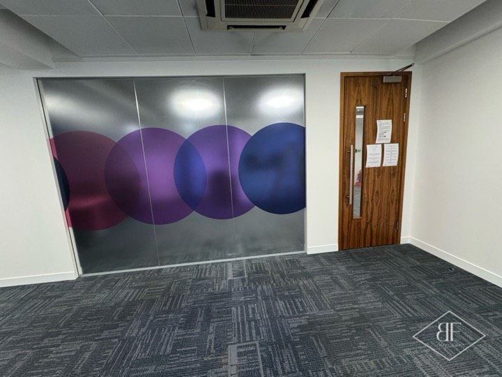 Frosted glass partition with circle graphic and walnut door in a finished room