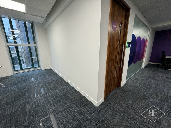 Finished white partition wall beside a timber door in a London open plan office