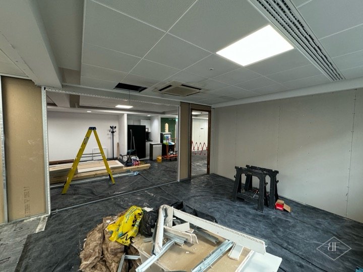 New boarded partition running across an office floor during the build