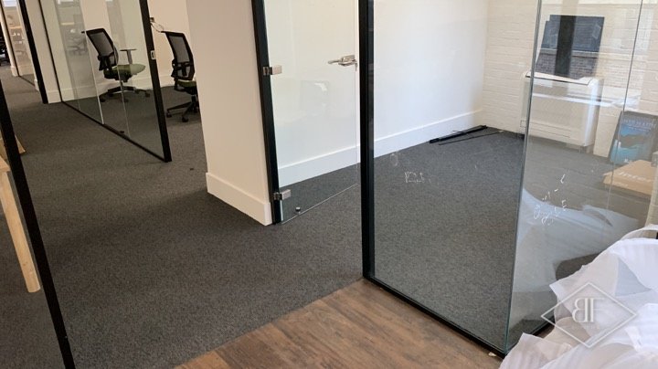 Black framed glass partition doors in a refurbished office corridor