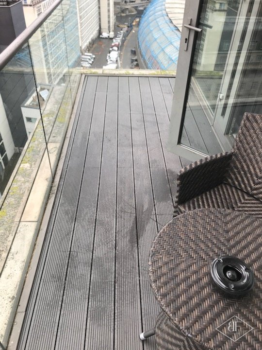 Weathered terrace decking before replacement beside open balcony doors