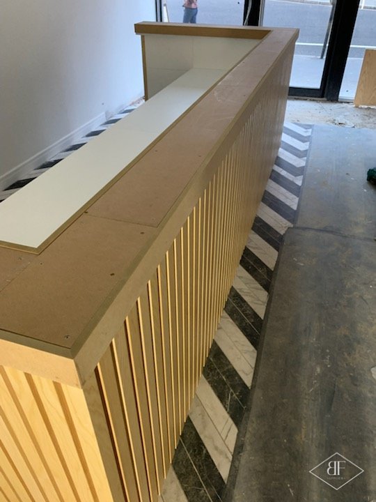 Close angled view of the slatted desk front and wide top during installation
