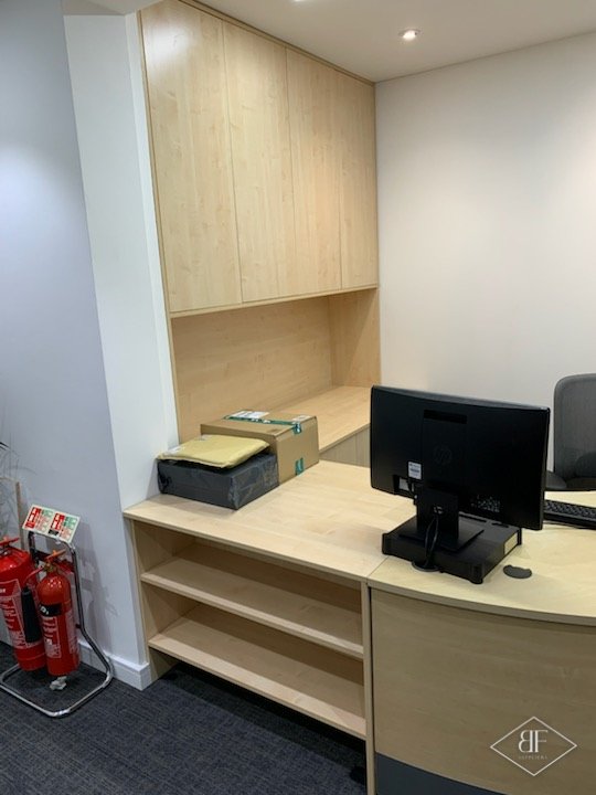 Reception workstation with open shelves, overhead cupboards and a curved desk end