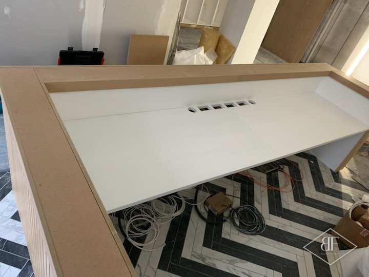 Top of reception desk with white inset panel and cable outlets on chevron floor