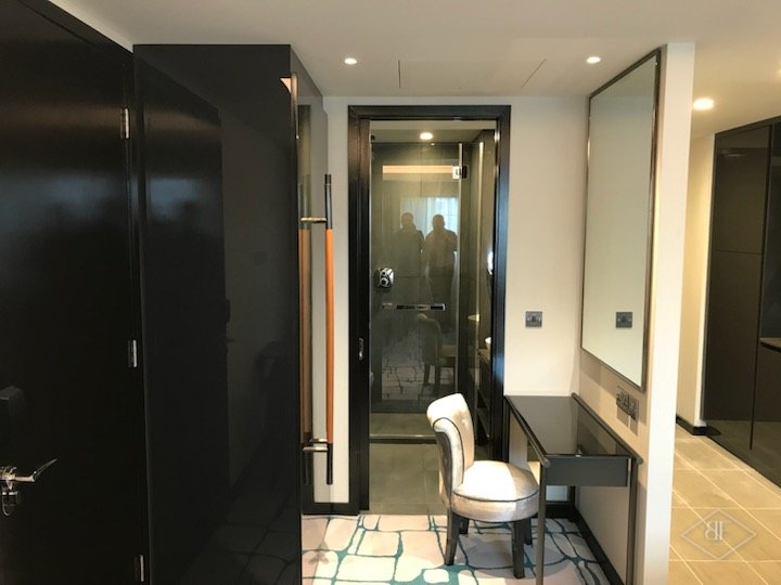 Dark glossy wardrobe doors and dressing area leading towards the bathroom