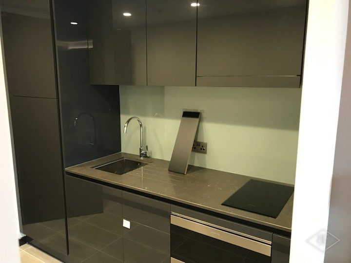 Dark compact kitchen with glass splashback, hob, oven and built-in cupboards