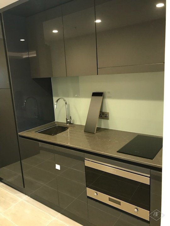 Close view of suite kitchenette with glossy dark units and downlights