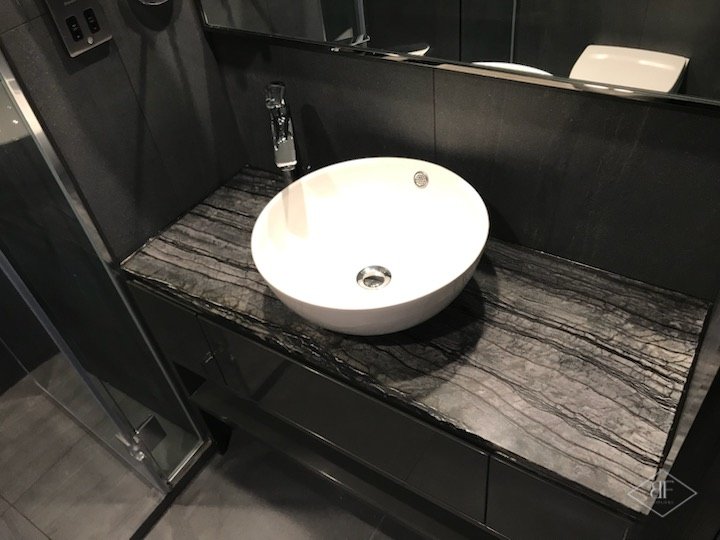 Bathroom vanity with veined dark stone top and white round basin