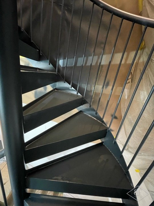 Close view of dark metal spiral treads and slim vertical balusters
