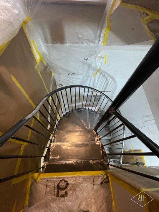 Looking down a spiral metal staircase wrapped in plastic sheeting