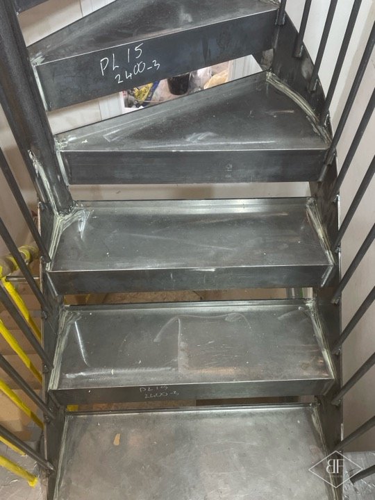 Steel stair treads before painting, with marker notes on the metal