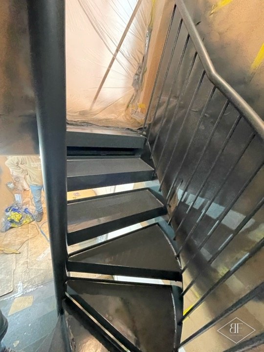 Metal staircase steps and handrail masked and prepared during the spraying stage