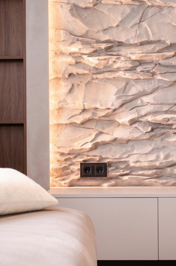 Backlit textured wall behind a bed