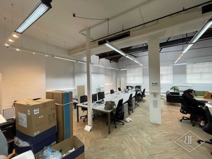 Open-plan studio office with herringbone flooring, white columns and desks