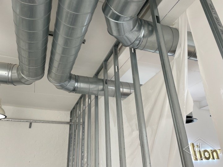 Metal stud framing for a new partition wall running around exposed office ducting