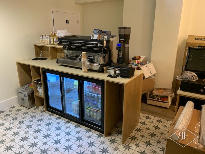 Coffee counter in oak with a cream top, drinks fridges below and star pattern floor tiles