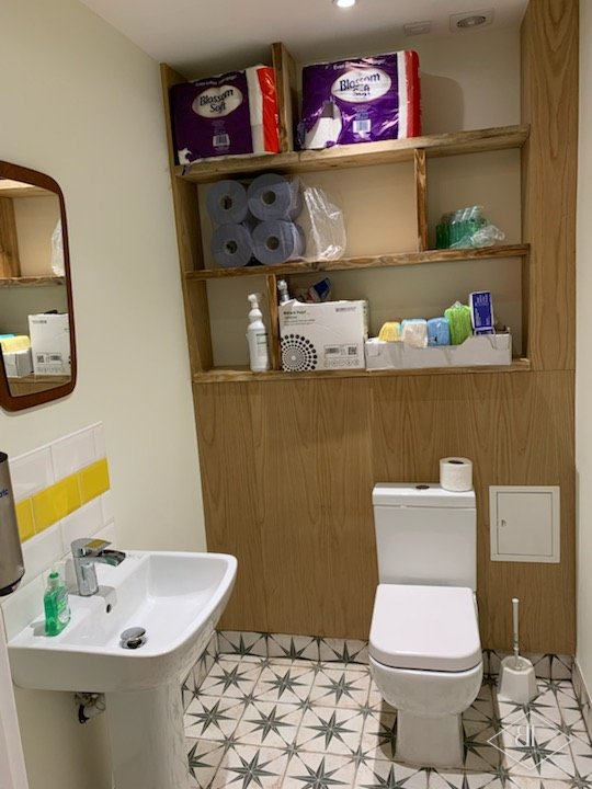 Cloakroom with oak panelling, open shelving above the toilet, white basin and star pattern tiles