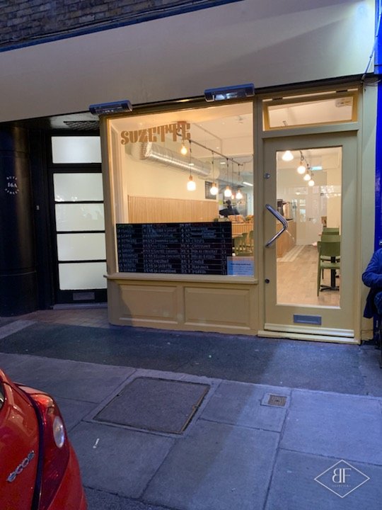 Cafe shopfront at night in South Kensington with the interior lit through the window