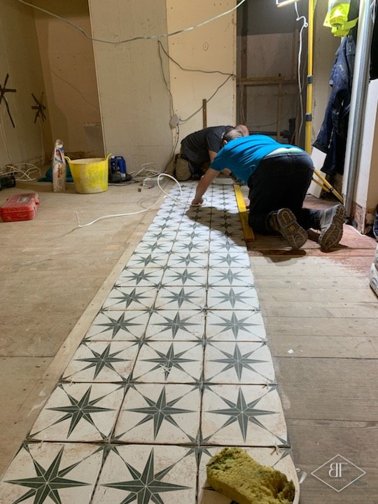Star pattern floor tiles being laid in a long run across the cafe floor