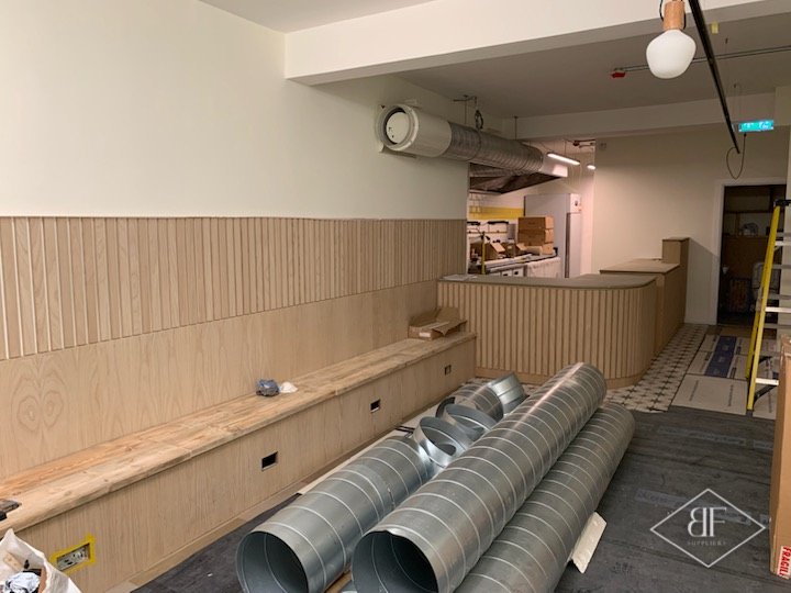 Long slatted panelled wall and bench running towards the bar, works under way