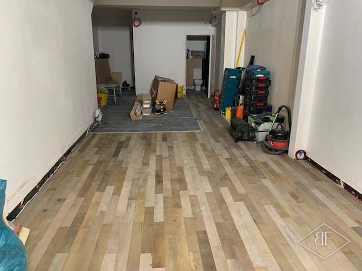 Newly laid wood effect flooring along the shop floor before fit-out