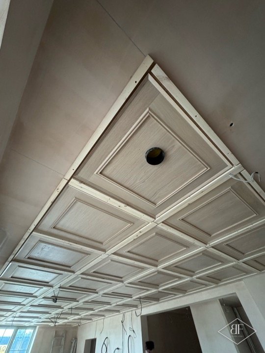 Wide view of a large oak coffered ceiling grid across an unfinished open-plan room
