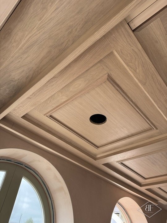 Detail of oak coffer moulding and a round spotlight cut-out beside arched windows