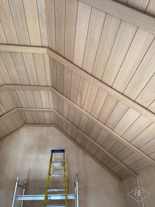 Pitched oak panelled ceiling with a stepladder below, ready for finishing