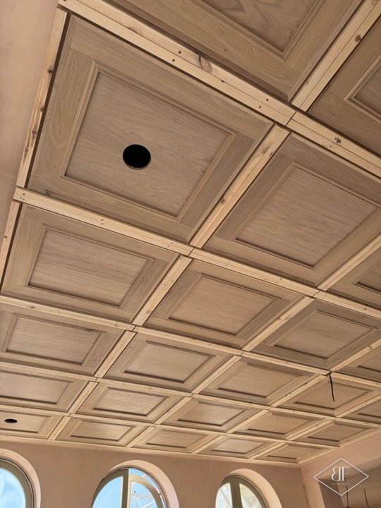 Coffered oak ceiling bays in a room with arched windows along the wall