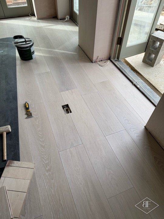 Wide plank engineered oak flooring being laid beside patio doors