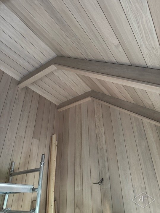 Vaulted ceiling clad in oak boards with exposed oak beam detail